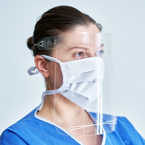 Dental team member with face mask and plastic shield