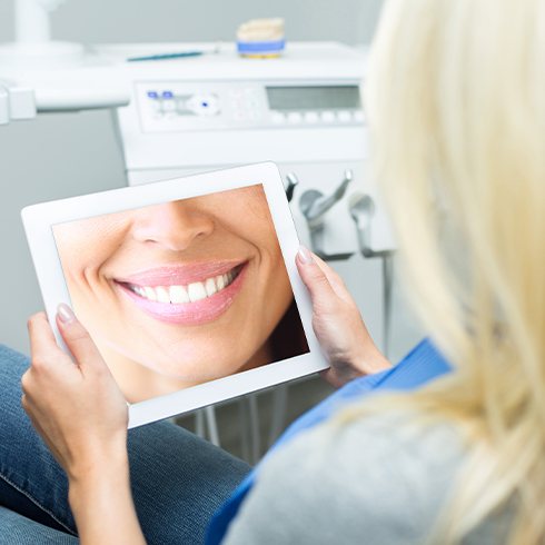 Woman looking at virtual smile design on tablet computer