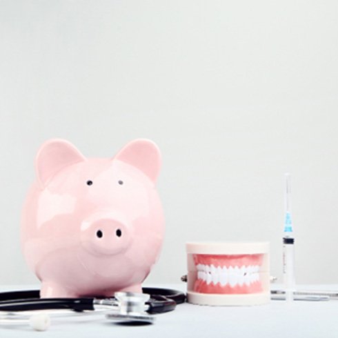 A piggy bank with a stethoscope and tooth model